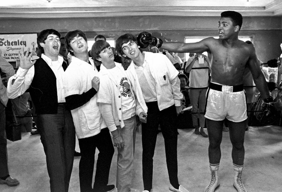 FILE - In this Feb. 18, 1964, file photo, The Beatles, from left, Paul McCartney, John Lennon, Ringo Starr, and George Harrison, take a fake blow from Cassius Clay, who later changed his name to Muhammad Ali, while visiting the heavyweight contender at his training camp in Miami Beach, Fla. Ali turns 70 on Jan. 17, 2012. (AP Photo/File) ORG XMIT: NY205